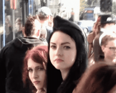 Woman In Black Hood Stands In Crowd GIF