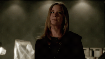 Woman In Black Hoodie Standing In Dark Room Looking At Camera GIF