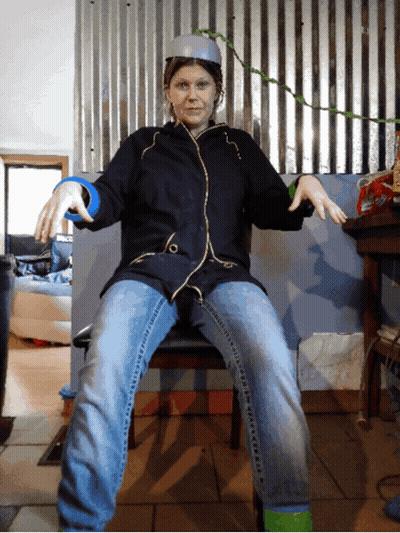 Woman In Black Jacket And Blue Jeans Sitting With Arms Outstretched GIF