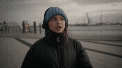 Woman In Black Jacket And Blue Knitted Hat Looking At Camera GIF