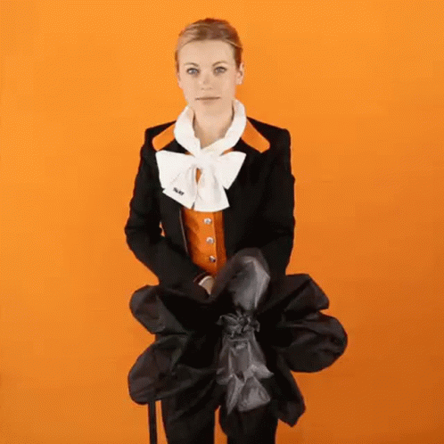 Woman In Black Jacket And Orange Vest Holding Bag GIF