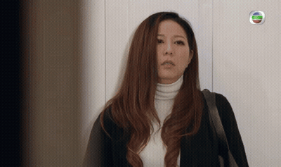 Woman In Black Jacket And White Turtleneck In Front Of TV Channel Logo GIF