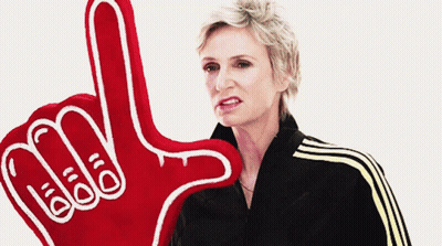 Woman In Black Jacket Holding Red Foam Hand Saying I Love You GIF