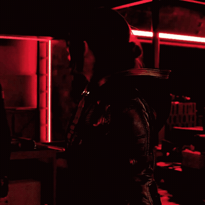 Woman In Black Jacket In Dark Room With Red Lights GIF
