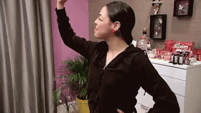 Woman In Black Jacket In Front Of Pink Wall GIF