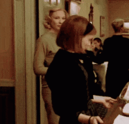 Woman In Black Jacket Standing In Hallway GIF