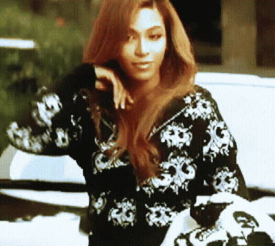 Woman In Black Jacket With White Flowers Next To White Car GIF