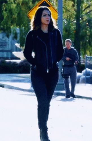 Woman In Black Leather Jacket Walking Down Street GIF
