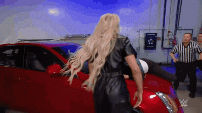 Woman In Black Leather Jumpsuit In Front Of Red Car GIF