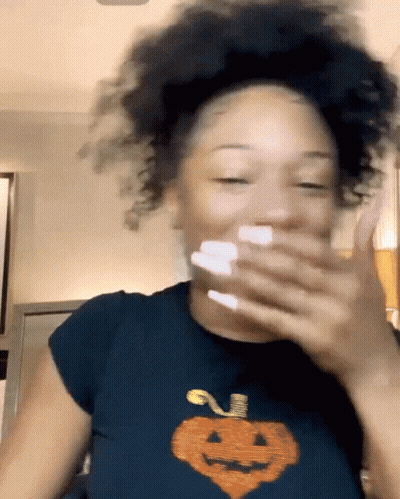 Woman In Black Pumpkin T-Shirt Covering Mouth GIF