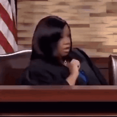 Woman In Black Robe Sitting At Courtroom Table GIF