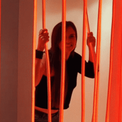 Woman In Black Shirt Behind Red Fence GIF