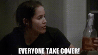 Woman In Black Shirt Holding Bottle Saying Everyone Take Cover GIF