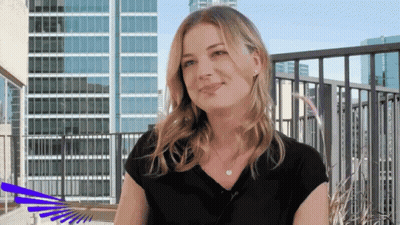 Woman In Black Shirt On Balcony In Front Of Tall Buildings GIF