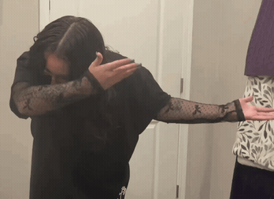 Woman In Black Shirt With Sheer Sleeves Covering Face GIF