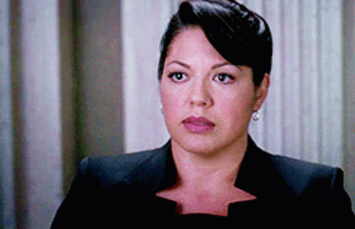 Woman In Black Suit And Earrings Looks At Camera GIF