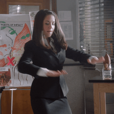 Woman In Black Suit Dancing Before Points Of Impact Board GIF