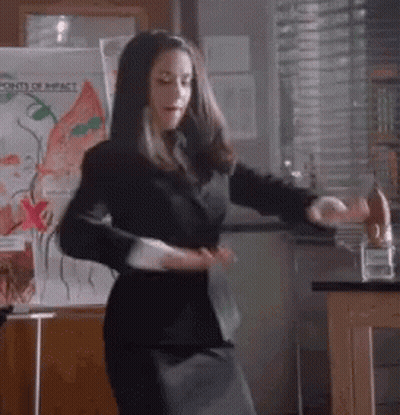 Woman In Black Suit Dancing Before Points Of Impact Board GIF