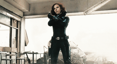 Woman In Black Suit Holding Gun With Avengers Belt GIF