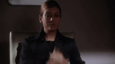 Woman In Black Suit Sitting With Hands Up GIF