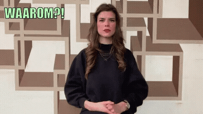 Woman In Black Sweater In Front Of Wall Saying Waarom GIF