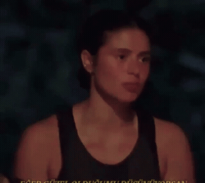 Woman In Black Tank Talking In Dark Room GIF
