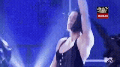 Woman in Black Tank Top Dancing in Front of MTV Sign