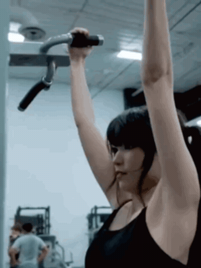 Woman In Black Tank Top Hanging On Gym Bar GIF