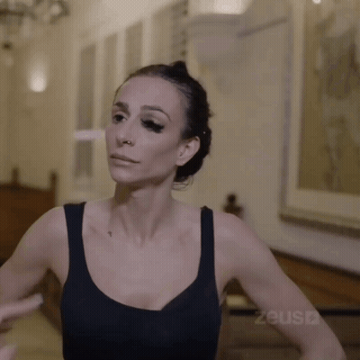 Woman In Black Tank Top In Front Of Zeus Advertisement GIF