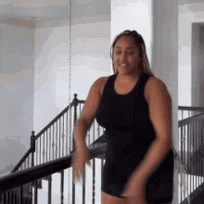 Woman In Black Tank Top Standing On Staircase GIF