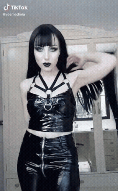 Woman In Black Top And Pants Standing In Front Of Mirror GIF