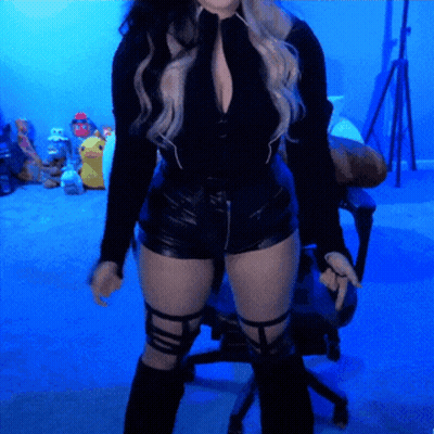 Woman In Black Top And Shorts Before Blue Wall GIF
