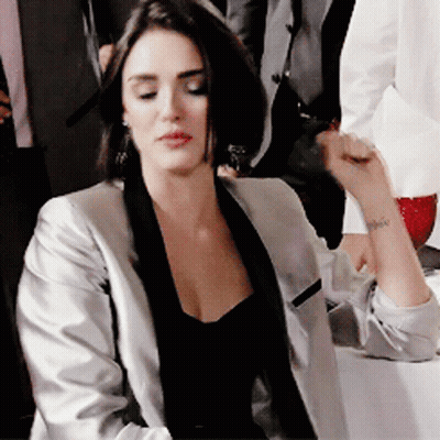 Woman In Black Top And Silver Jacket With Wrist Tattoo GIF