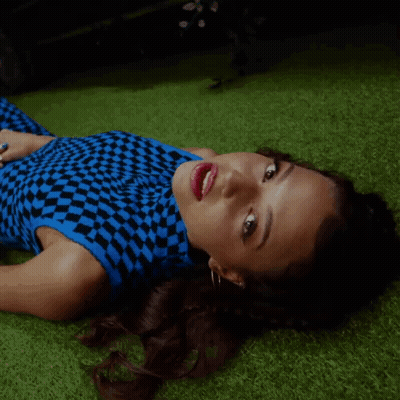 Woman In Blue And Black Checkered Top Laying On Grass GIF