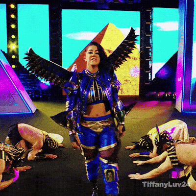 Woman In Blue And Gold Costume With Wings In Front Of Pyramid GIF
