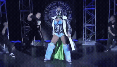 Woman In Blue And Green Outfit In Front Of King Of Sports Banner GIF