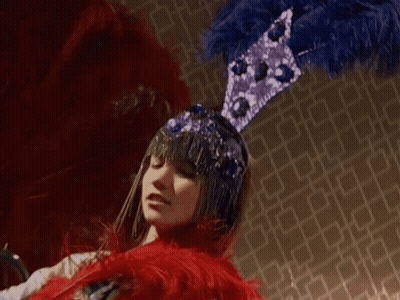 Woman In Blue And Purple Feathered Hat GIF