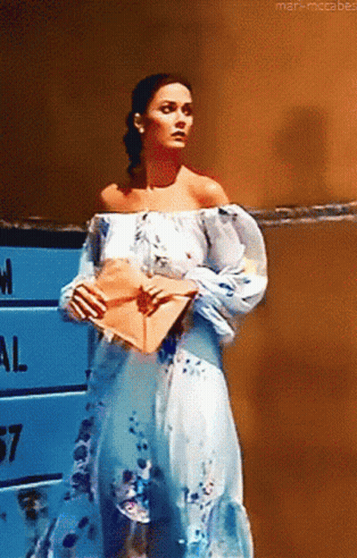 Woman In Blue And White Dress Holding Envelope In Front Of National Sign GIF