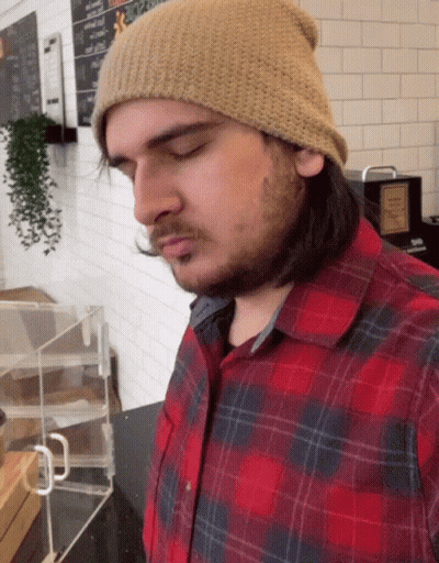 Woman In Blue Cardigan And Green Tank Top By Window With Blinds GIF