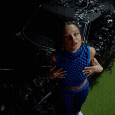 Woman In Blue Checkered Top And Blue Pants In Front Of Car GIF