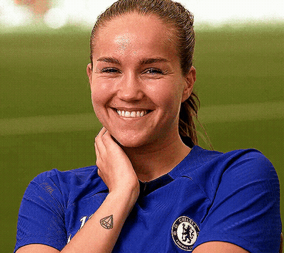 Woman In Blue Chelsea Shirt Smiling With Hand On Face GIF
