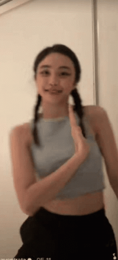 Woman In Blue Crop Top And Black Shorts Smiling Waving GIF