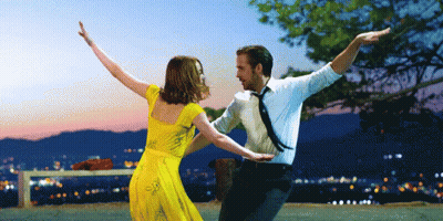 Woman In Blue Dress And Necklace Looking At Camera GIF