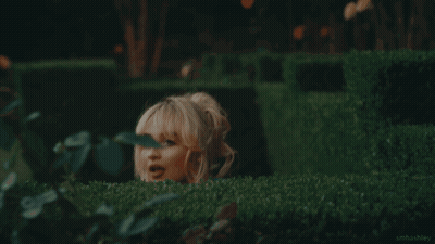 Woman In Blue Dress Hiding Behind Hedge GIF