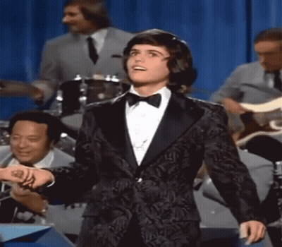 Woman In Blue Dress Holding Glass Asks About Love Spell GIF