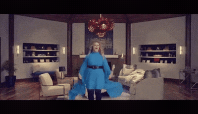 Woman In Blue Dress In Living Room With Couch And Chairs GIF