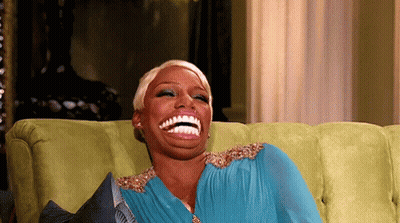 Woman In Blue Dress Laughing On Green Couch GIF