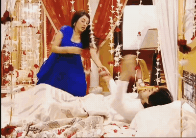 Woman In Blue Dress Next To Man In White Dress On Bed GIF