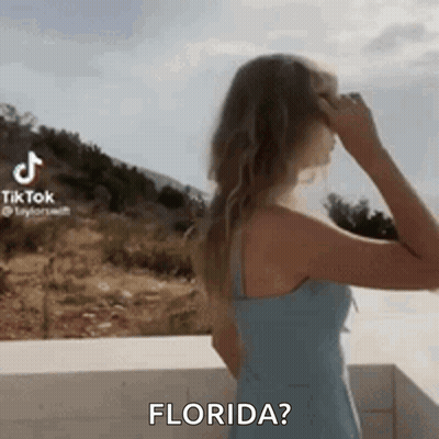 Woman In Blue Dress On Balcony Hand In Hair Asking Florida GIF