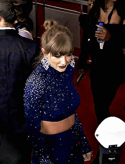 Woman In Blue Dress On Red Carpet With Man In Striped Sweater GIF